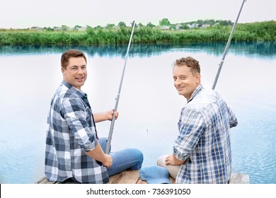 Two Men Fishing From Pier On River