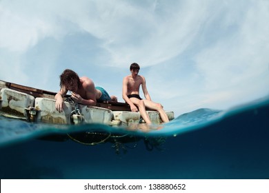 Two men floating in a sea on a plastic raft