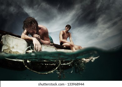 Two men floating in a sea with sad faces and wounds on a body