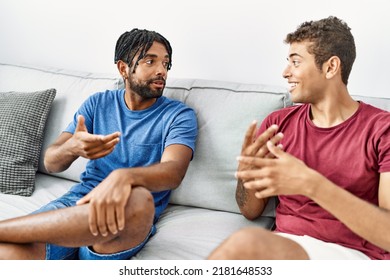 Two Men Friends Having Conversation Sitting On Sofa At Home