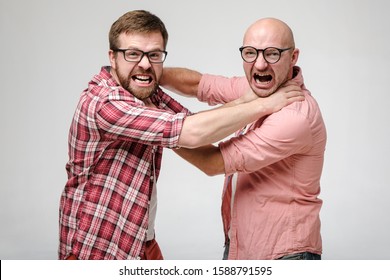 Two men in glasses strangle each other, they look furiously at the camera, grin their teeth and scream.