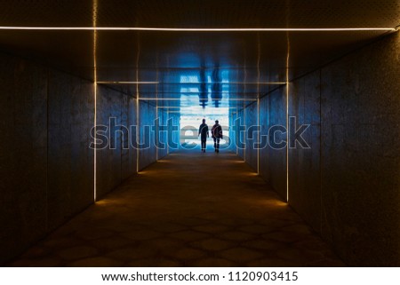Two men are going from the light insight the dark surrealistic tunnel with concentric light stripes, Moscow, Russia