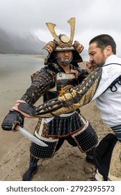 Two men grapple in authentic samurai armor during an intense shoreline duel at Stave Lake, Mission, British Columbia, Canada.