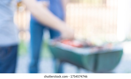 Two Men Grill BBQ To Socialize With A Beer On Their Hands During Covid 19's Holidays With Blurred Pictures.