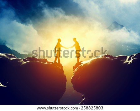 Two men handshake over mountains precipice. Business, deal, connection concepts