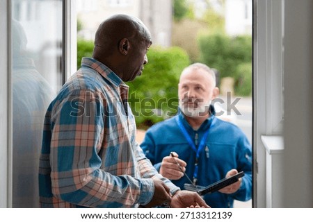 Two men having a conversation at a front door during daytime in a residential neighborhood