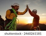 Two men high on a mountain, one of them is wearing a yellow jacket. They are high up on a mountain and are high fiveing each other