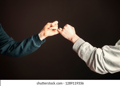 Two Men Hold Their Little Fingers And Make Peace