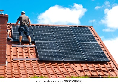 Two men installing new solar panels on the roof of a private house. Renewable energy concept and green energy abstract. - Shutterstock ID 2004938930