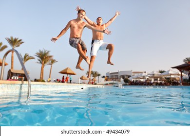 Two men jumping in swimming pool together.  Low angle view from the swimming pool. - Powered by Shutterstock