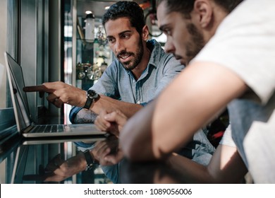 Two men looking at laptop computer and discussing ideas and designs at a sports shop. Man pointing at the screen and explaining ideas. - Powered by Shutterstock