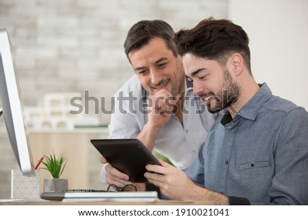 two men looking at tablet screen in an office