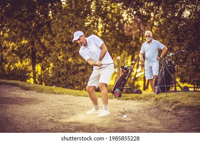 Two men on the golf course. Man hits a golf ball.