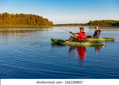 
Two men on kayaks fish in sunny weather on a lake
