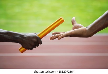 Two men passing golden baton in stadium. Conceptual image shot