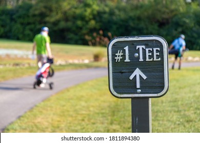 Two men playing golf walking past a sign for the first tee - Shutterstock ID 1811894380