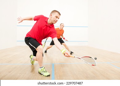 Two men playing match of squash. Closeup of squash players in action on squash court 