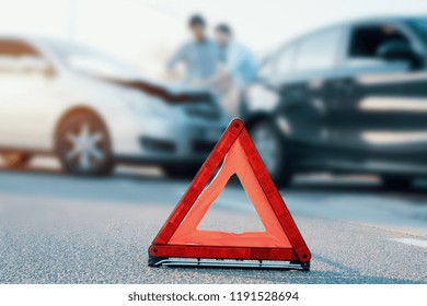 Two men reporting a car crash for the insurance claim,main focus on red triangle
