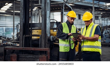 Two men in safety gear are looking at a tablet. They are wearing yellow vests and hard hats - Powered by Shutterstock