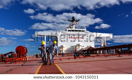 Two men (sailors) are working on deck of supertanker