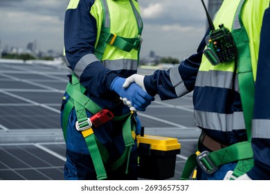 Two men shake hands while wearing safety gear. Scene is professional and serious. The idea of the image is that the two men are working together in a high-risk environment