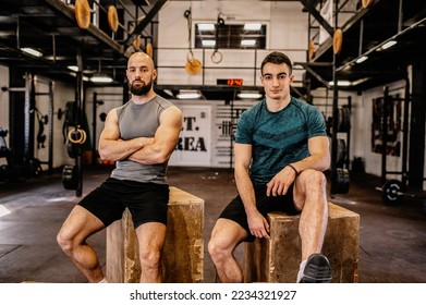 Two men sit on wooden boxes and look at the camera. Resting after a hard workout. - Powered by Shutterstock