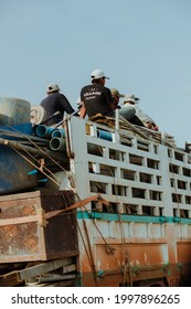 Two Men Sitting On Top Of A Fully Loaded Truck