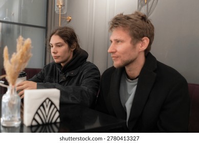 Two men are sitting at a table in a cafe, deep in conversation as they enjoy their drinks.