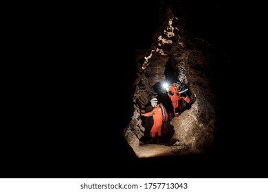 Two men, strong physique, explore the cave. Men dressed in special clothes to pass through the cave and stopped, looking at the map. - Powered by Shutterstock