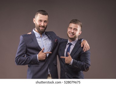 Two Men In Suits Hugging And Point The Finger At Each Other
