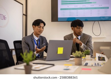 Two men in suits are looking at a computer screen with graphs and charts. They are discussing the data and making decisions based on the information presented. The atmosphere is serious and focused
