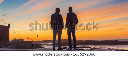 Two men at sunset on the ocean, Essaouira, Morocco