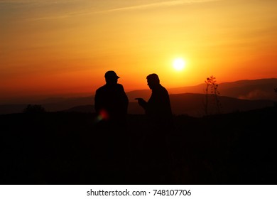 two men talking at sunset