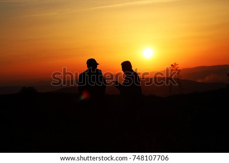 two men talking at sunset