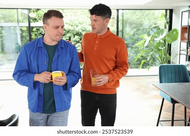 Two men talking while walking in living room.