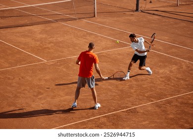 Two men, tennis players in motion on outdoor clay court, showing game skills and teamwork cooperation, playing with focus. Concept of sport, competition, active and healthy lifestyle - Powered by Shutterstock