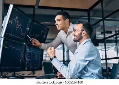 Two men traders sitting at desk at office together monitoring stocks data candle charts on screen analyzing price flow smiling cheerful having profit teamwork concept - Shutterstock ID 1805164180