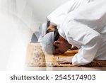 Two men in traditional Islamic attire, engaged in prayer. Islamic men, dressed in white, are bowing in prayer. Islamic prayer scene highlights the men