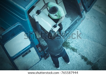Two men unload cardboard boxes from van