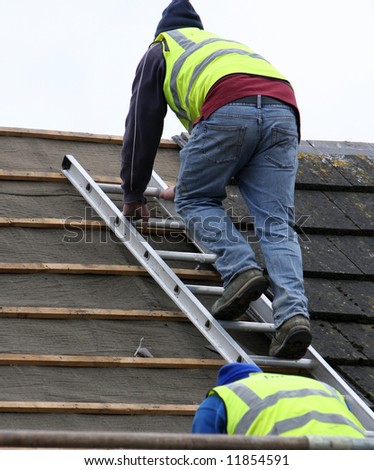 Two men using the roofing ladder to take slates off