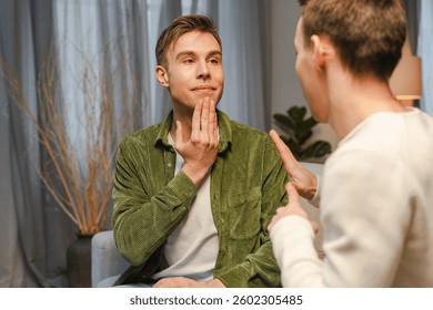 Two men are using sign language to communicate, practicing their skills in a comfortable home environment. Sign language concept