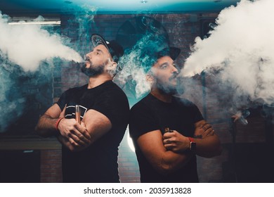Two men vaping in an authentic room with brick walls. Vaping an electronic cigarette with a lot of smoke