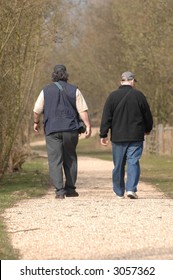 Two Men Walking Away From View Along A Country Track