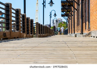 Two men walking down an old wooden boardwalk near a historic downtown port