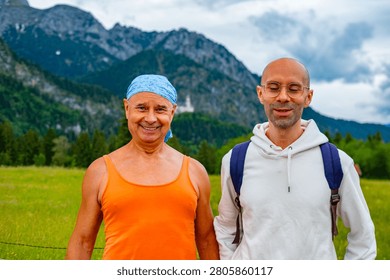Two men walking path nature mountains, Father and son, older man orange tank top blue bandana younger man white hoodie glasses backpack hiking tourism Bavaria Germany summer day, Generational bonding