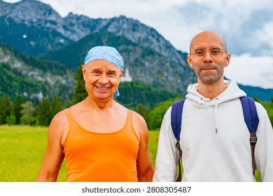 Two men walking path nature mountains, Father and son, older man orange tank top blue bandana younger man white hoodie glasses backpack hiking tourism Bavaria Germany summer day, Generational bonding