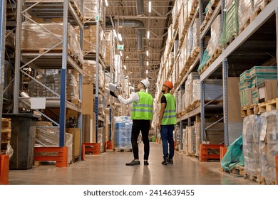 two men in warehouse wearing safety helmet, vest. Concept for industry, job, meeting, work training. Two caucasian warehouse workers walking in distribution storage area discussing - Powered by Shutterstock