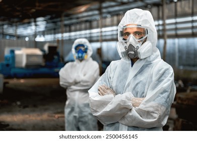 Two men in white protective gear stand in a factory. One of them is wearing a gas mask - Powered by Shutterstock