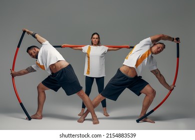 Two men and woman aikido fighters with wooden fight stick posing in studio, fight demonstration