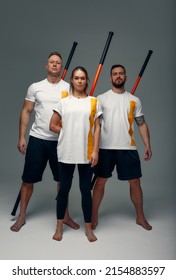 Two men and woman aikido fighters with wooden fight stick posing in studio, fight demonstration. Sport banner